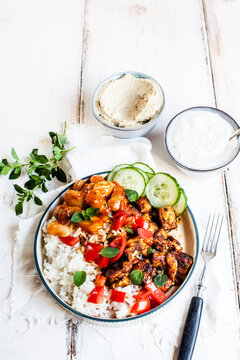 Bowl of Greek gyro with rice, fava beans, halloumi cheese, tomatoes and cucumbers
