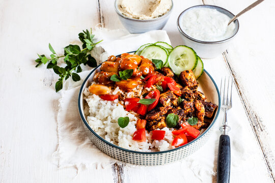 Bowl of Greek gyro with rice, fava beans, halloumi cheese, tomatoes and cucumbers