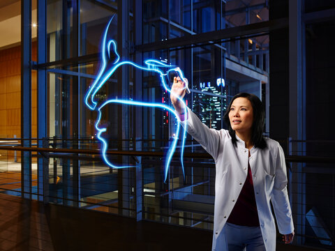 Mature female otolaryngologist light painting nasal in laboratory at hospital