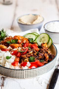 Bowl of Greek gyro with rice, fava beans, halloumi cheese, tomatoes and cucumbers