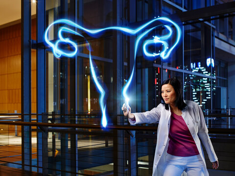 Mature female gynecologist examining ovary with light painting in laboratory at hospital