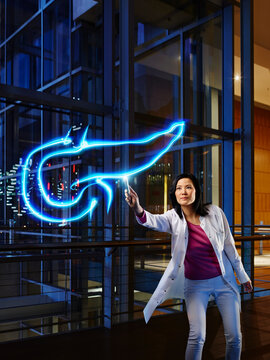 Mature female internist light painting pancreas in laboratory at hospital