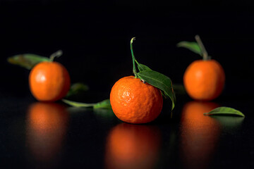Fresh tangerine with leavers lies on a black table in the black background. Selective focus. New Year.