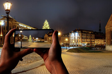 Tourist taking photo of Dome Square with Christmas tree in Riga's Old Town, Riga, Latvia