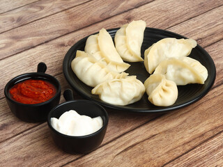 Paneer steam momo. Nepalese Traditional dish Momo stuffed with paneer and then cooked and served with sauce and mayonnaise over a rustic wooden background, selective focus