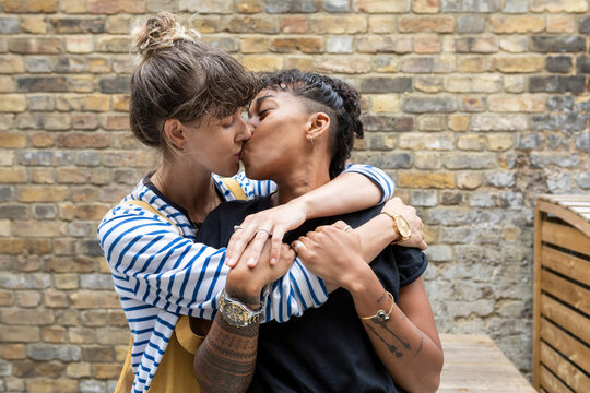 Lesbian couple kissing each other while standing at back yard