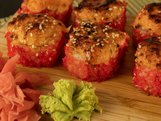 Fish and cucumber rolls in red caviar, on a wooden board,