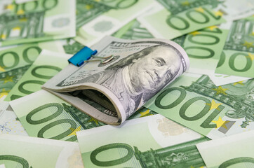 100 dollars squeezed with a metal clip on euro background, set of banknotes, European currency,
