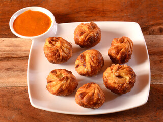 Veg fried momo with sauce served over a rustic wooden background, selective focus