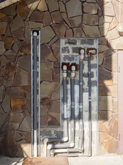 Plastic pipes in the wall with decorative masonry with roof shade and sunlight outside