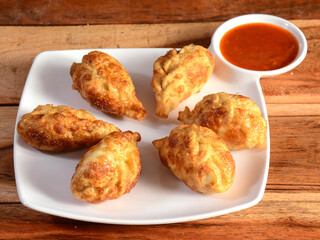 Veg fried momo with sauce served over a rustic wooden background, selective focus