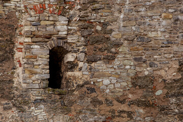 Fototapeta na wymiar Medieval old stone wall, with a small window, defensive structure, fort. Natural texture, a copy space.