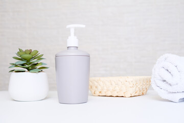 Spa salon and bathroom interior in pastel colors, gray soap dispenser, white towel and potted plant for spa, body and face care