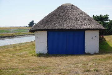 Fototapeta na wymiar traditional rural house with thatched roof by the water canal in Vendée, France