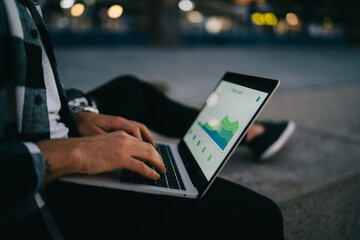Cropped image of man freelancer banking and making transaction during remote job outdoors via 4G connection, male digital nomad typing on laptop computer making report for marketing strategy