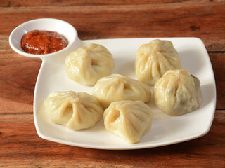 Veg steam momo. Nepalese Traditional dish Momo stuffed with vegetables and then cooked and served with sauce over a rustic wooden background, selective focus