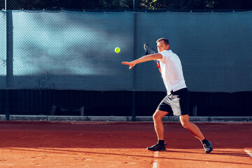 Proffesional tennis player beats off a ball during match