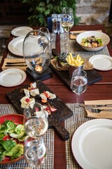 table served for dinner. on a wooden table assorted cheeses, fries, salad and burger.
