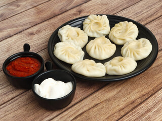 Veg steam momo. Nepalese Traditional dish Momo stuffed with vegetables and then cooked and served with sauce over a rustic wooden background, selective focus