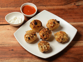 Veg tandoori momo. Nepalese Traditional dish Momo stuffed with vegetables and then cooked and served with sauce and mayonnaise over a rustic wooden background, selective focus