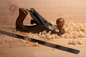 an old carpenter plane and a steel ruler on a wooden background with shavings