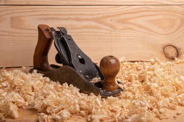 an old carpenter plane on a wooden background with shavings