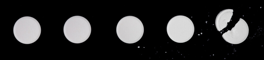 a white broken tablet in a row of wholes. on black background