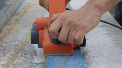 Electro shirt and old boards. The hands of a worker with a tool on wood