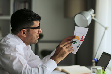 Busy male businessman checking financial reports at home, Young businessman analyzing  and working with documents.