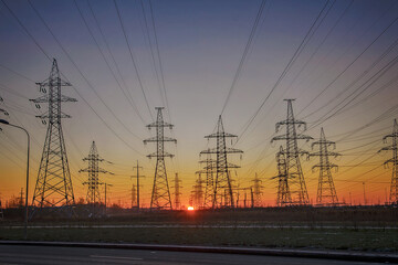 Fototapeta na wymiar Silhouettes of a high-voltage electric tower against the background of sunrise and sky. Power line.