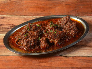 Bhuna Gosht Mutton masala OR Indian Lamb Curry is authentic indian spicy lamb gravy dish.Cooked with Indian spices,served over a rustic wooden background, selective focus