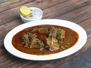 Mutton curry or Lamb curry, spicy and delicious dish served over a rustic wooden background, selective focus