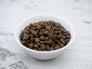 Brown grains of invigorating coffee in a white bowl