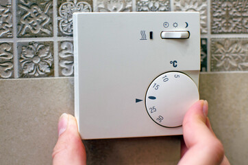 Closeup of hand using floor temperature controller at home