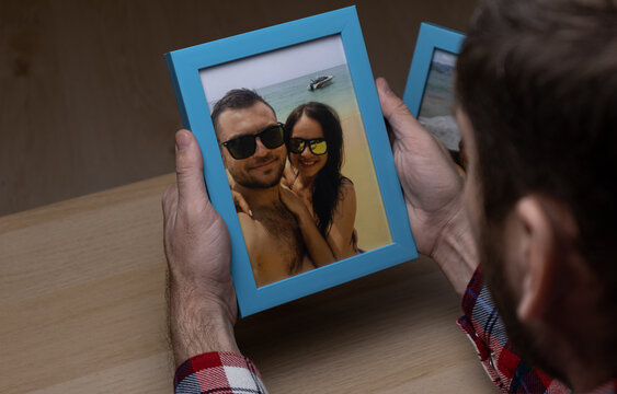 Man looking at photo frame with happy travelling couple of young people. Pictures and memories.