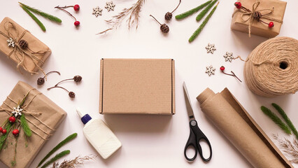 Step 1.Step by step instruction to eco friendly and zero waste Christmas gift wrapping.Gift box,brown paper,rope,glue,scissors and natural plants for decoration,top view,flat lay.