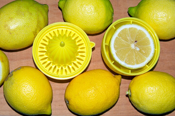 lemon squeezer with lemons around, on wooden background. top view, selective focus