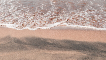 Fototapeta na wymiar Transparent sea waves on the warm sandy seashore. Sea vacation and travel.
