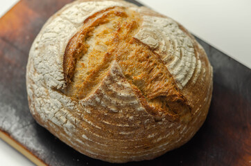 Traditional round loaf of bread baked according to a classic recipe, served on a wooden board