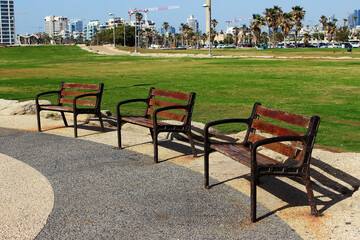 Benches on the promenade on the beach in tel Aviv against the background of the city. The Givat Aliya Beach. Tel Aviv, Israel.