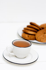 A cup of tea and oatmeal cookies. Breakfast. Tea drinking. White wooden background.