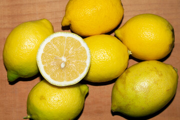 half lemon on other lemons, on wooden background. top view, selective focus