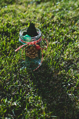 Christmas decorations in a jar with ribbon in the grass in a garden