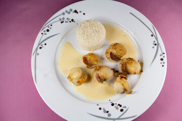 Plate of grilled scallops with rice and cream sauce