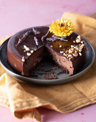 Chocolate cake with yellow flower and yellow napkin on pink backdrop