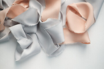 grey and peach silk ribbons on a light background . sewing theme . the view from the top . space for text.
