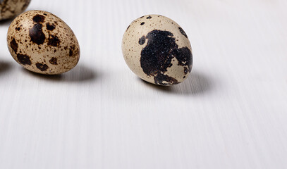 Obraz premium two quail eggs with different shells on a light wooden table. Large and small drawing. Healthy food concept