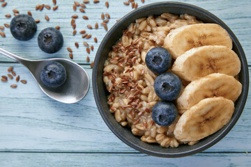 Whole grain oatmeal with blueberries and banana slices in a dark grey bowl