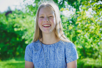 Fototapeta premium portrait of a smiled girl with long blond hair of twelve years old outdoor