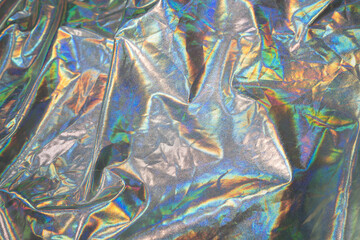 Obraz na płótnie Canvas Sparkling colored fabric holographic background. Holographic iridescent surface wrinkled foil pastel